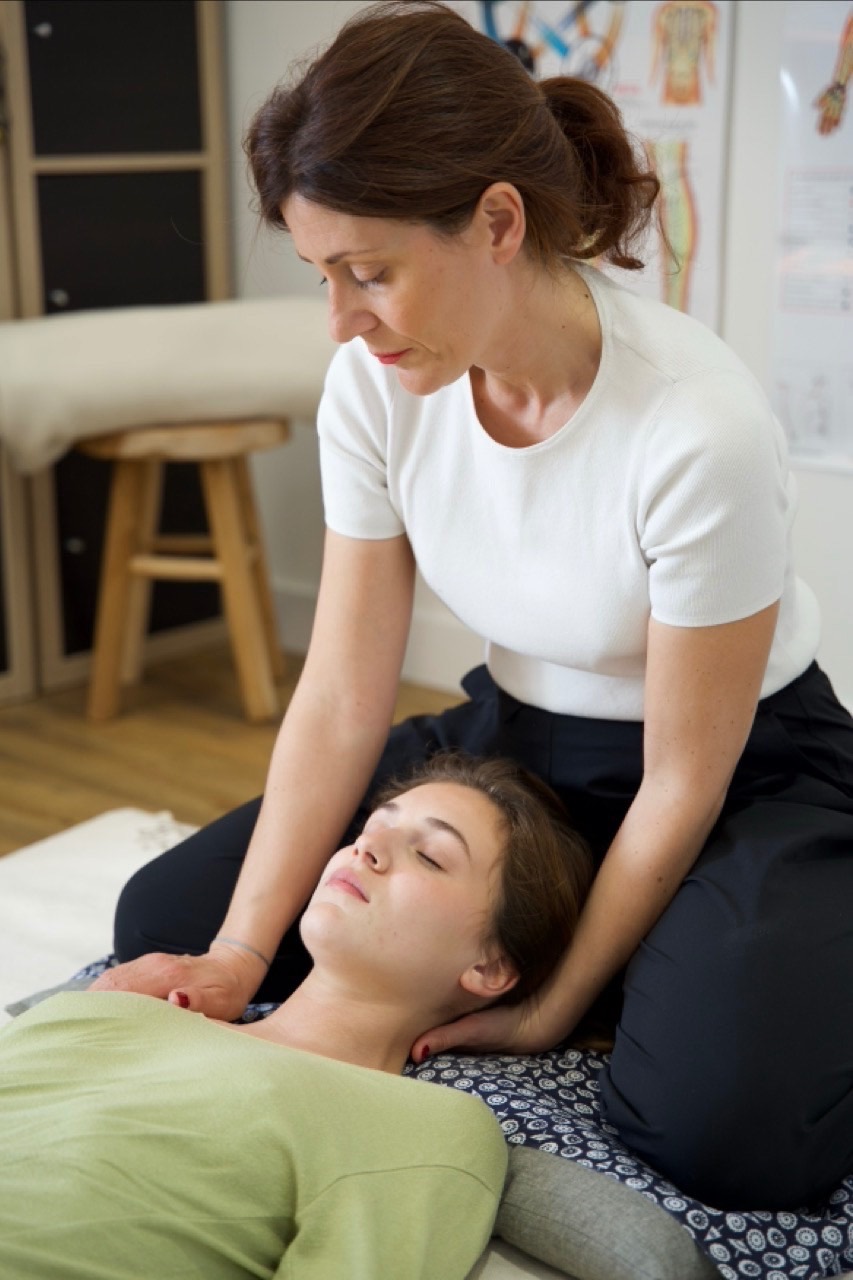 Séance de shiatsu — Solène Canivet travaillant sur la nuque et les épaules d'une cliente allongée sur futon